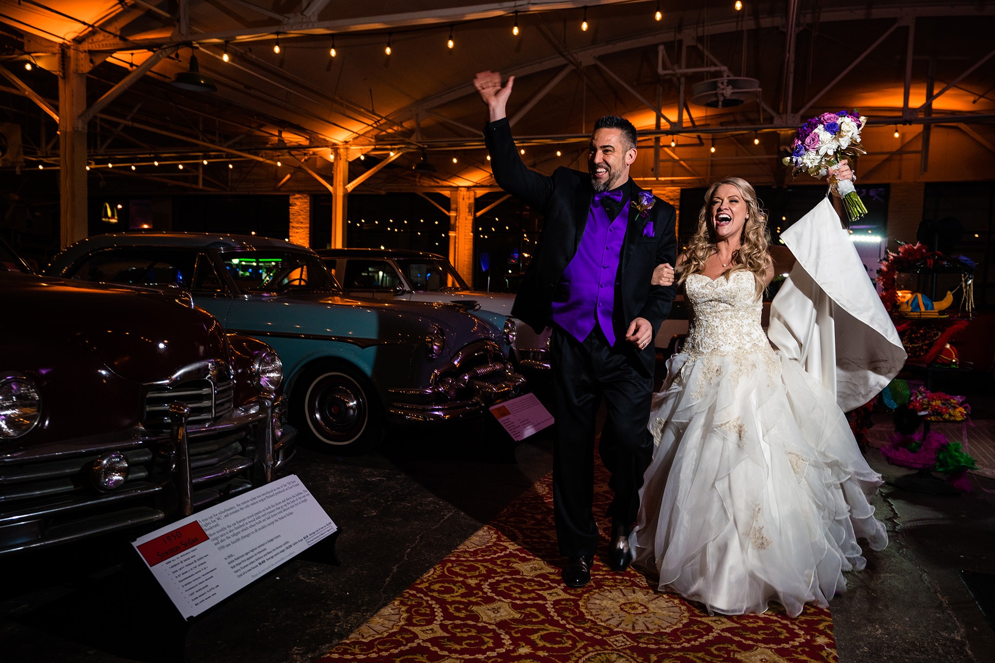 Bride and groom walking into their wedding reception, arms raised at America's Packard Museum by Dayton Wedding Photographer Studio 22 Photography