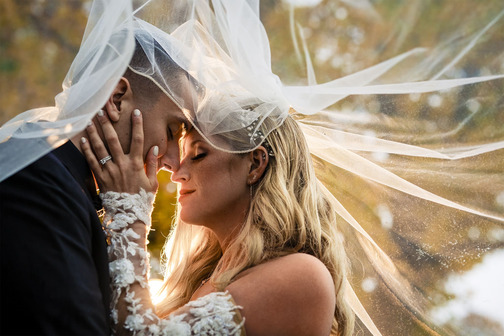 Bride touches groom's face under wedding veil