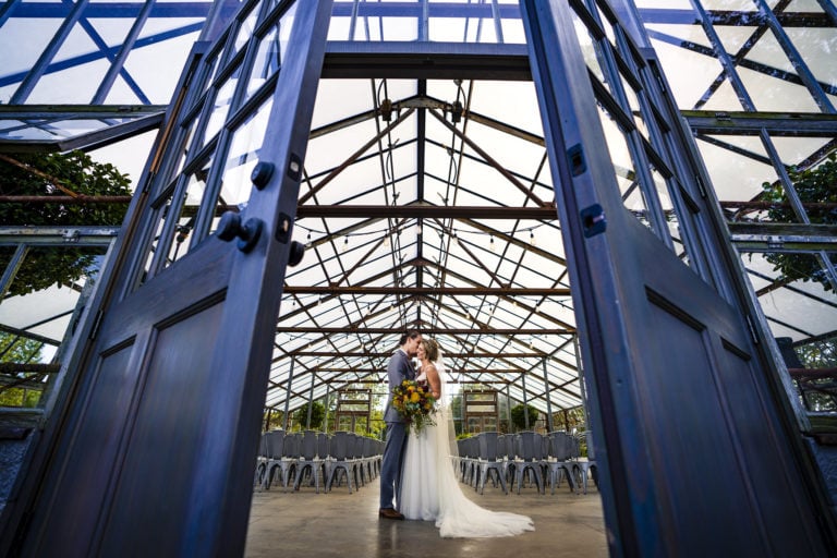 Bride and Groom kissing in greenhouse