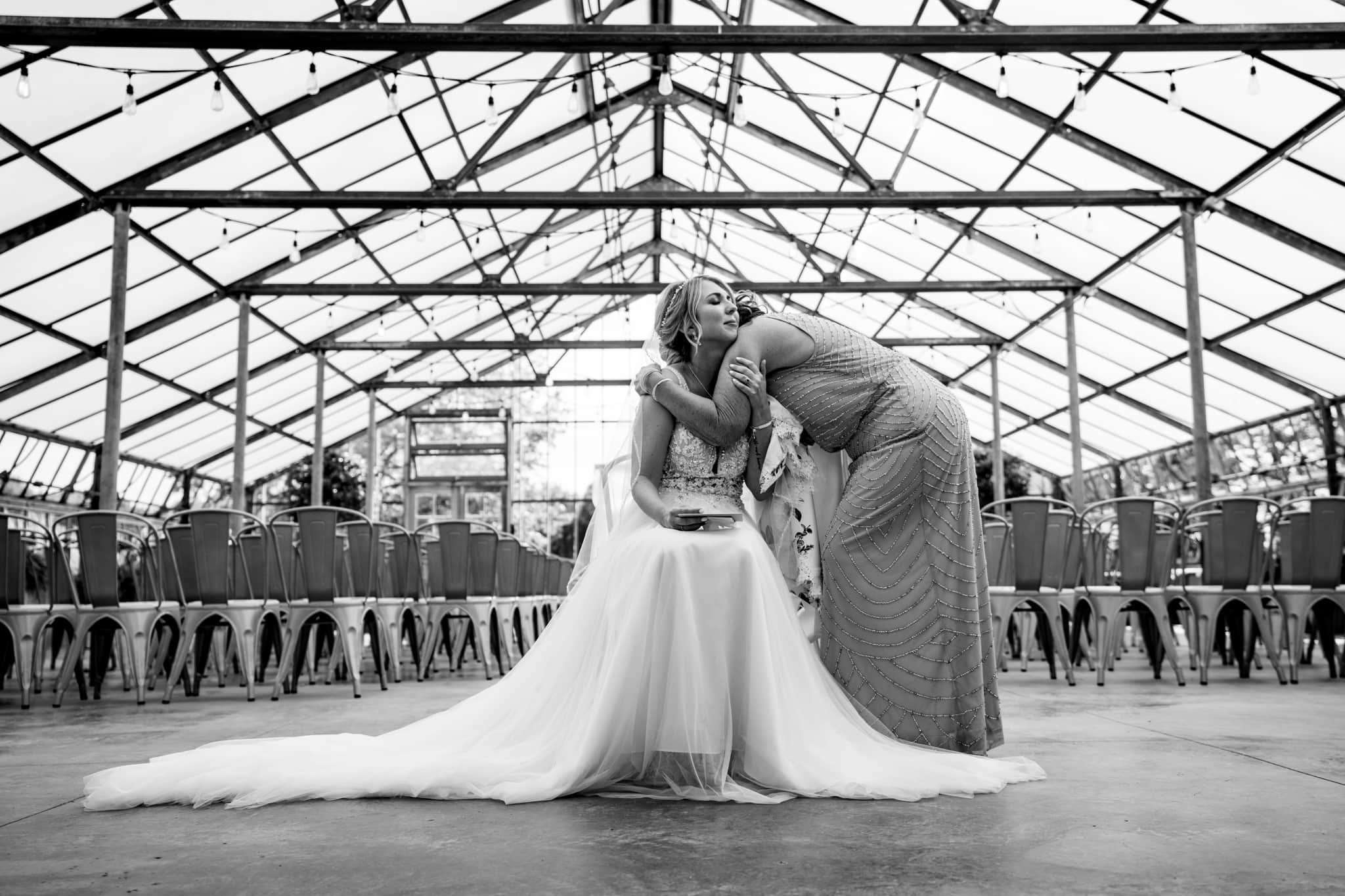 Mother hugs daughter at wedding in greenhouse